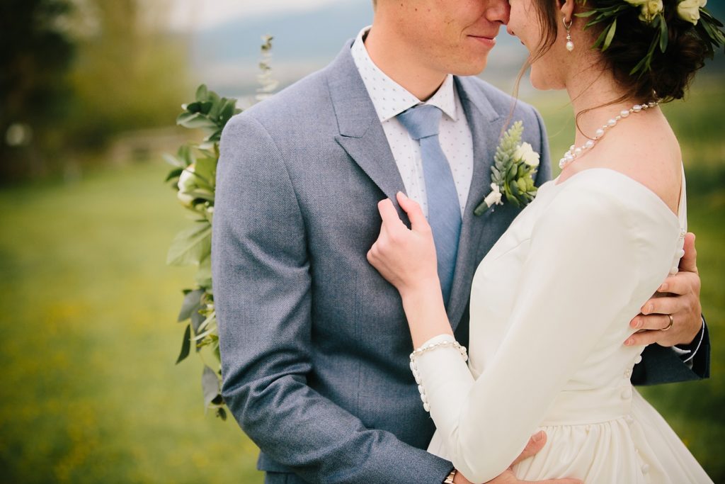 bride holding groom's suit to bring him closer during outdoor portraits