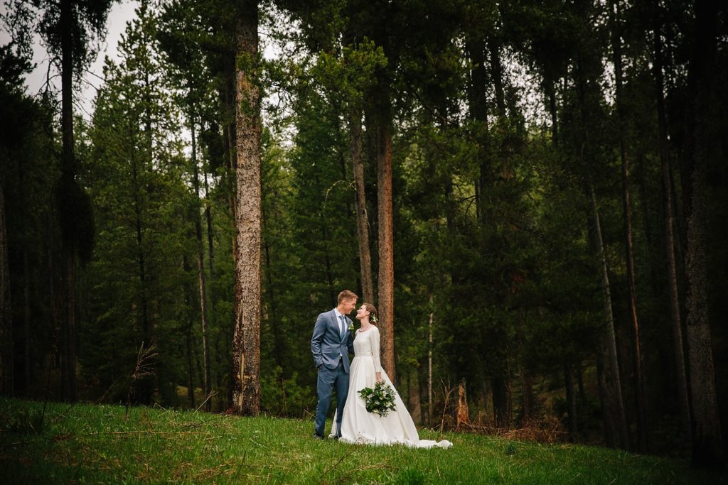 Jackson Hole wedding photographer captures couple standing in front of forest during budget friendly jackson hole wedding