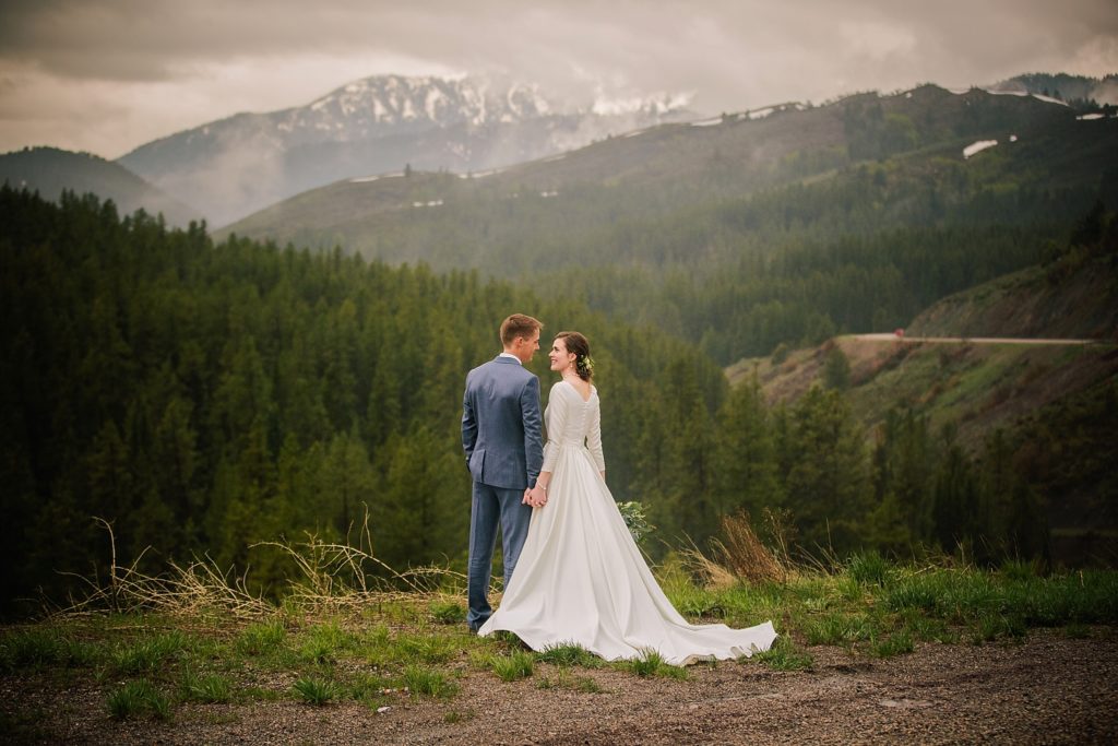 bride and groom standing together looking at mountains and view after Minimalistic and Earthy Idaho Falls Wedding  