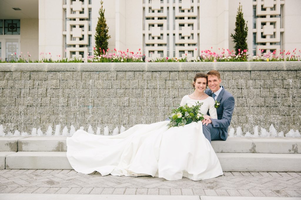 bride and groom sitting together in front of temple after Minimalistic and Earthy Idaho Falls Wedding ceremony