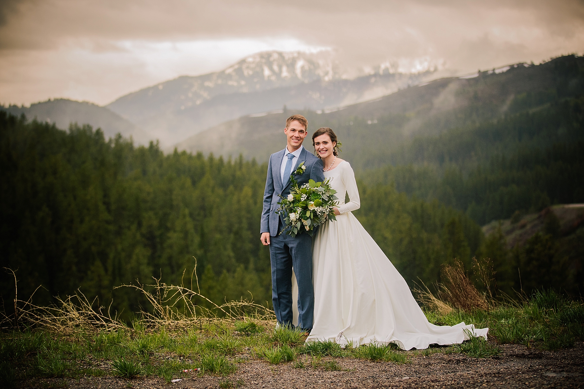 Jackson Hole wedding photographer captures bride and groom standing on top of mountain during outdoor bridals