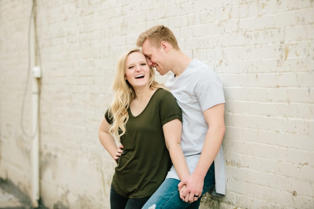 couple leaning against wall smiling