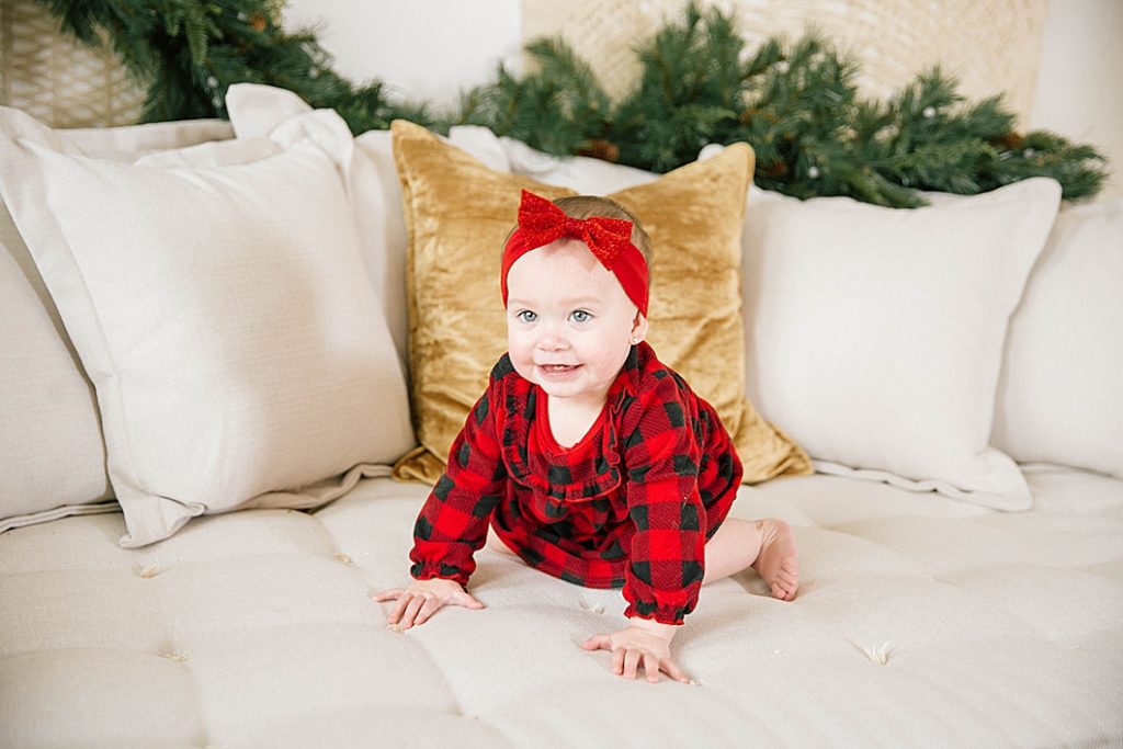baby climbing on couch wearing plaid christmas pajamas