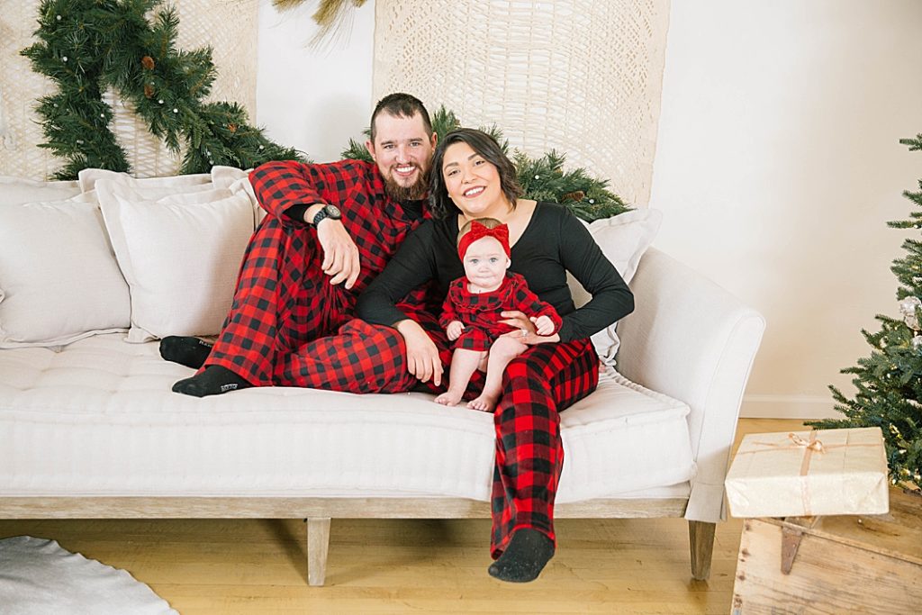 family sitting on couch smiling during christmas portraits