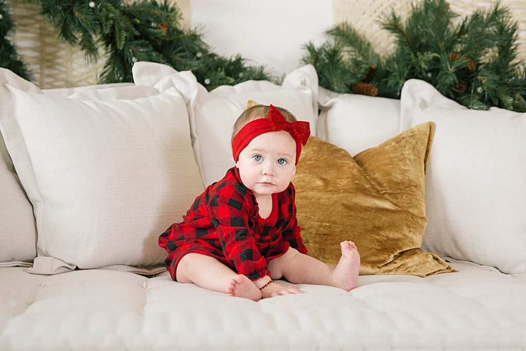 baby crawling on couch wearing red headband and pj's