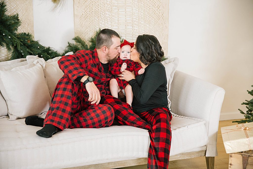 parents kissing baby on cheeks during pocatello christmas photography