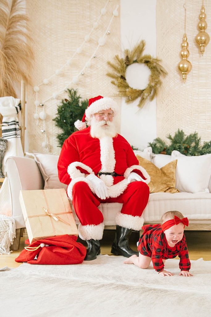 baby crawling on floor while santa watches