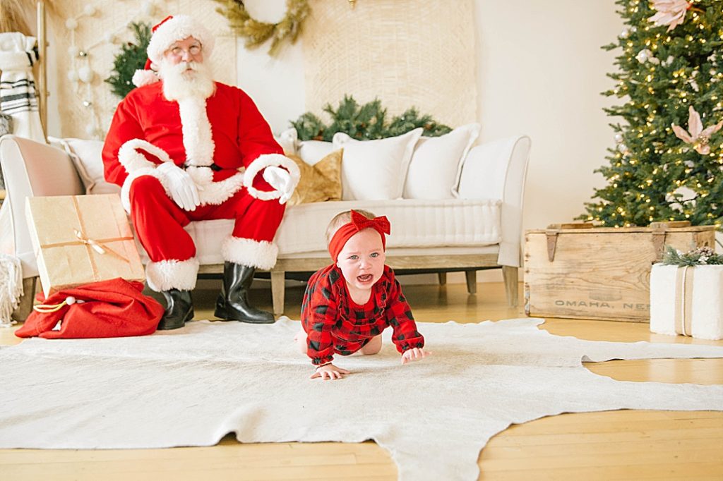 santa sitting on couch watching baby crawl away