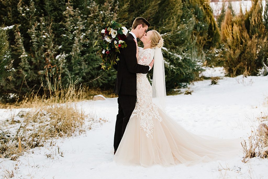 Snowy Pocatello wedding Bride and groom gaze into each others eyes next to pine trees at winter session