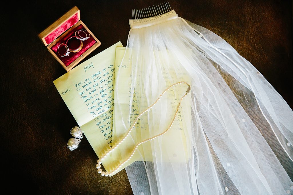 brides wedding veil and wedding rings sitting next to a letter