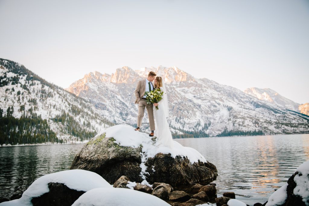 Man and woman kissing on rock in Jackson Hole during outdoor elopement
