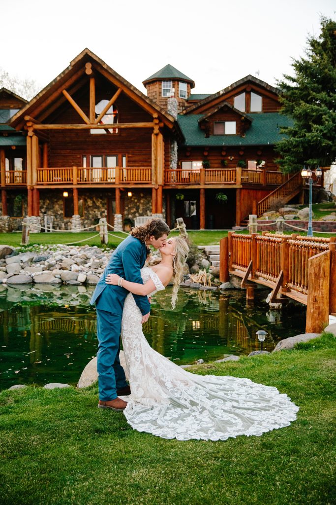 groom dipping his bride backwards as he kisses her outside in front of their wedding venue in Idaho