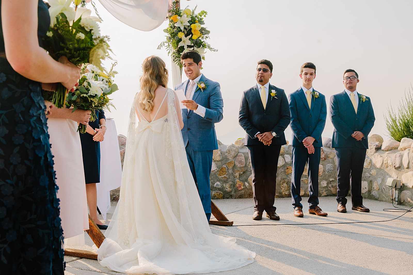 groom reading his wedding vows at his outdoor wedding with his groomsmen standing behind him