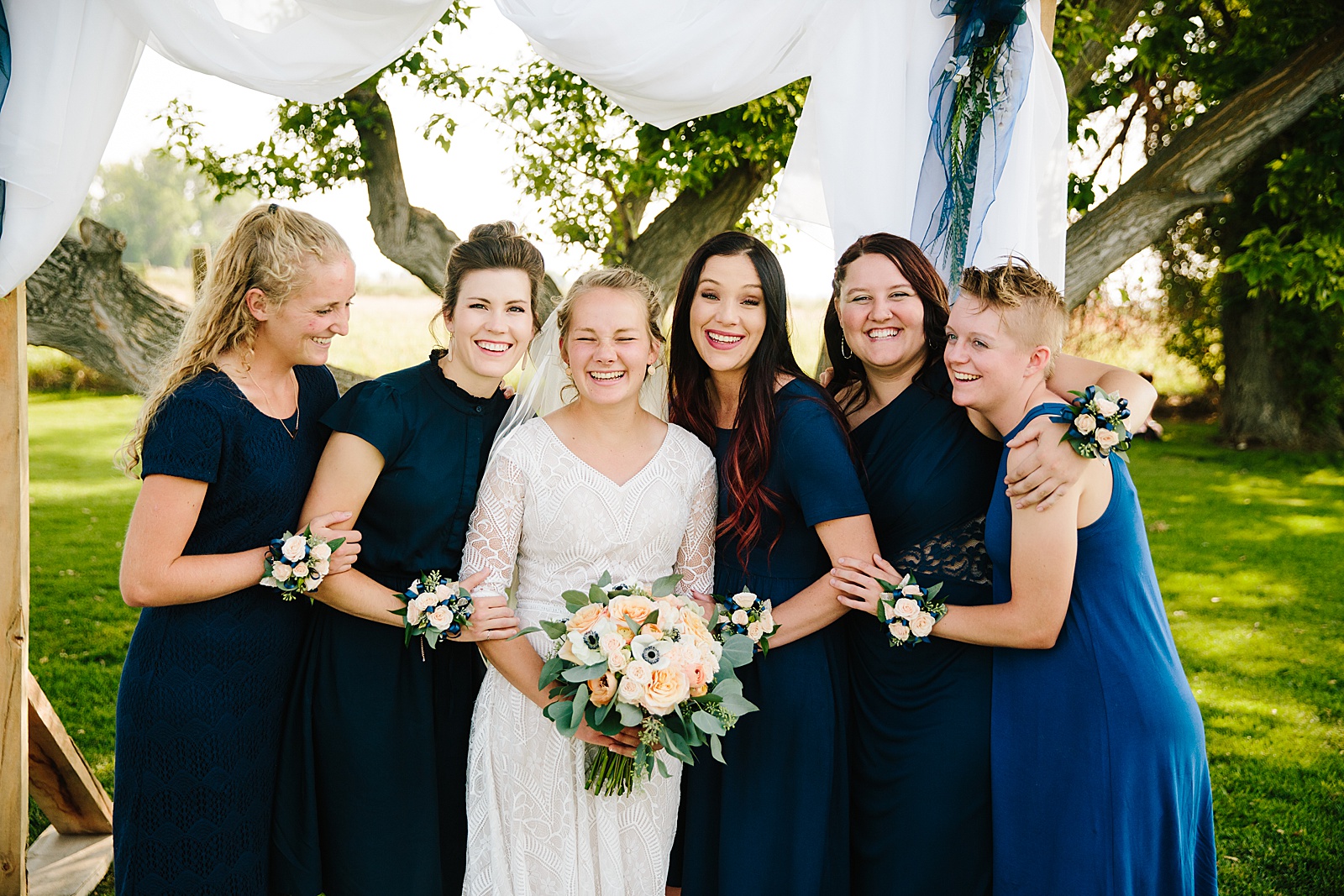 bride with her bridesmaids that are wearing dark blue bridesmaids dresses