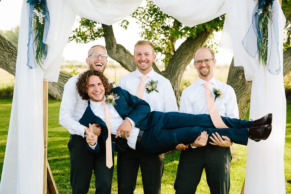 groomsmen photo with groom being held by his best friends 