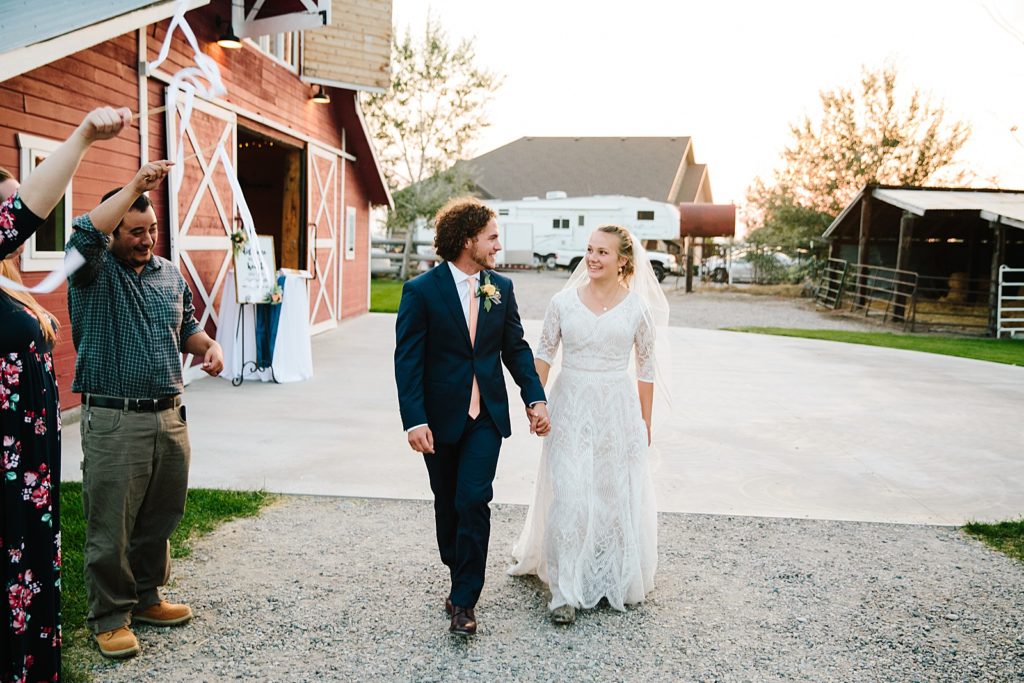 bride and groom holding hands and walking away from their red barn wedding day for their wedding send off