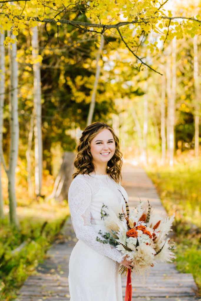 bride wearing long sleeve lace gown holding fall styled bridal bouquet 