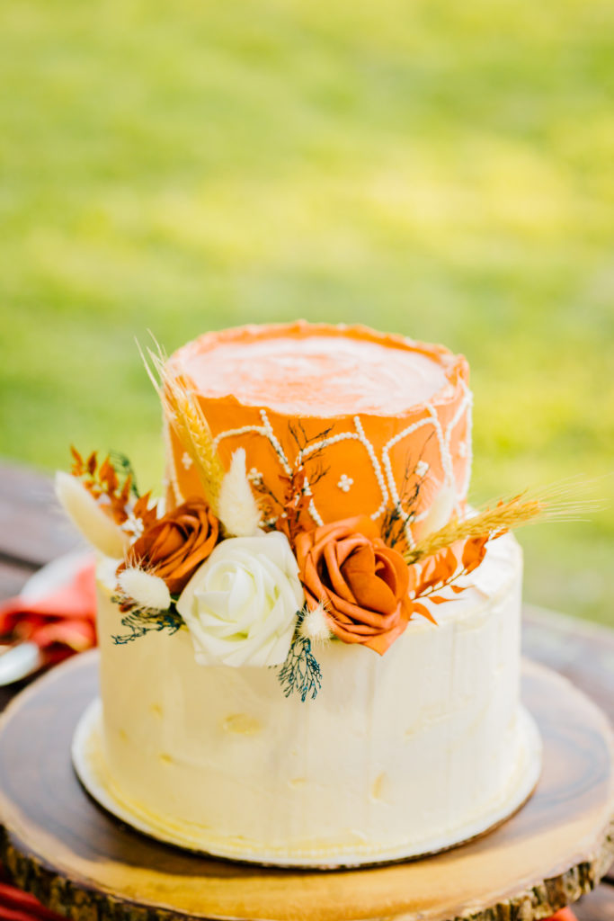 orange and cream wedding cake with boho florals