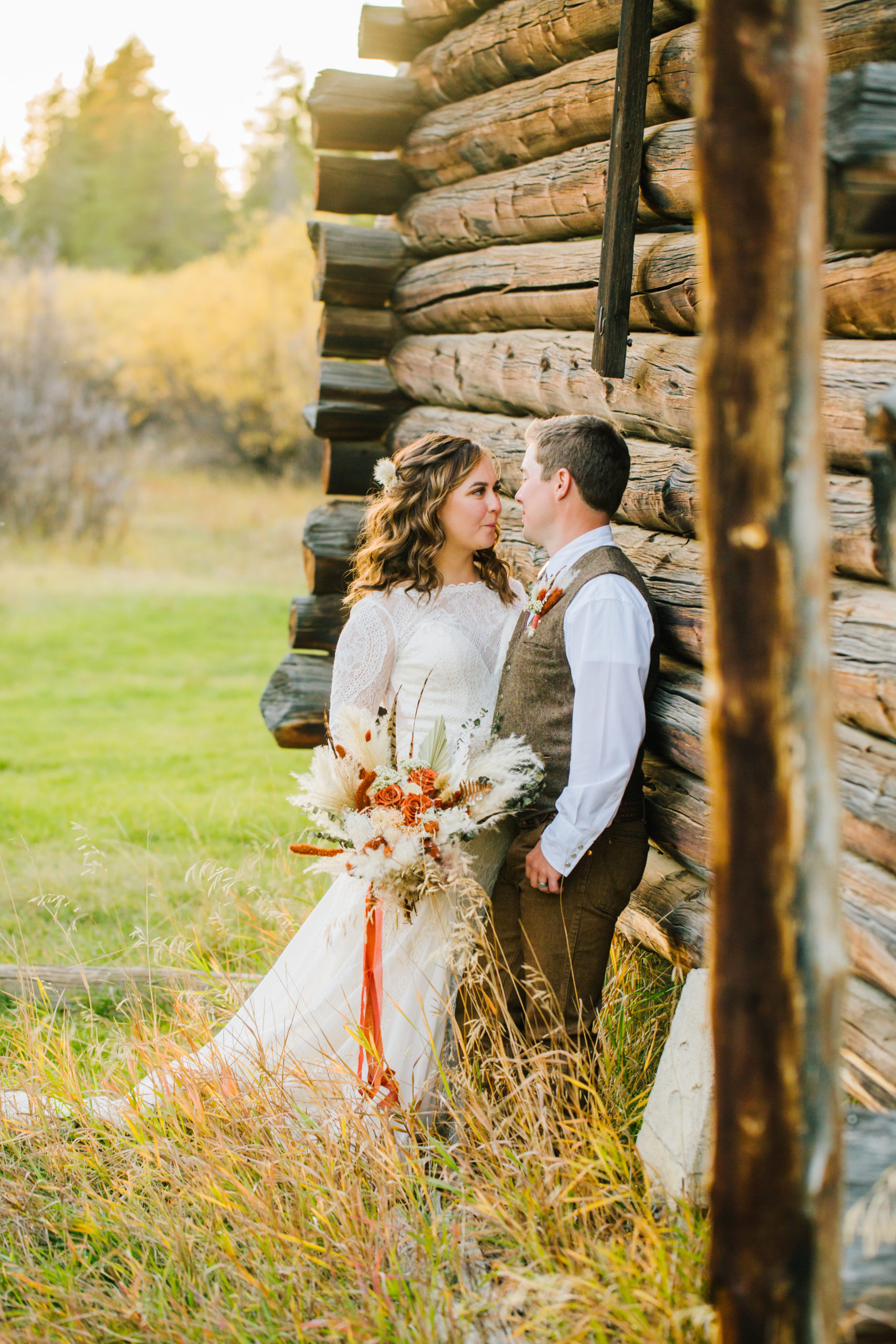 bride and groom leaning against cabin