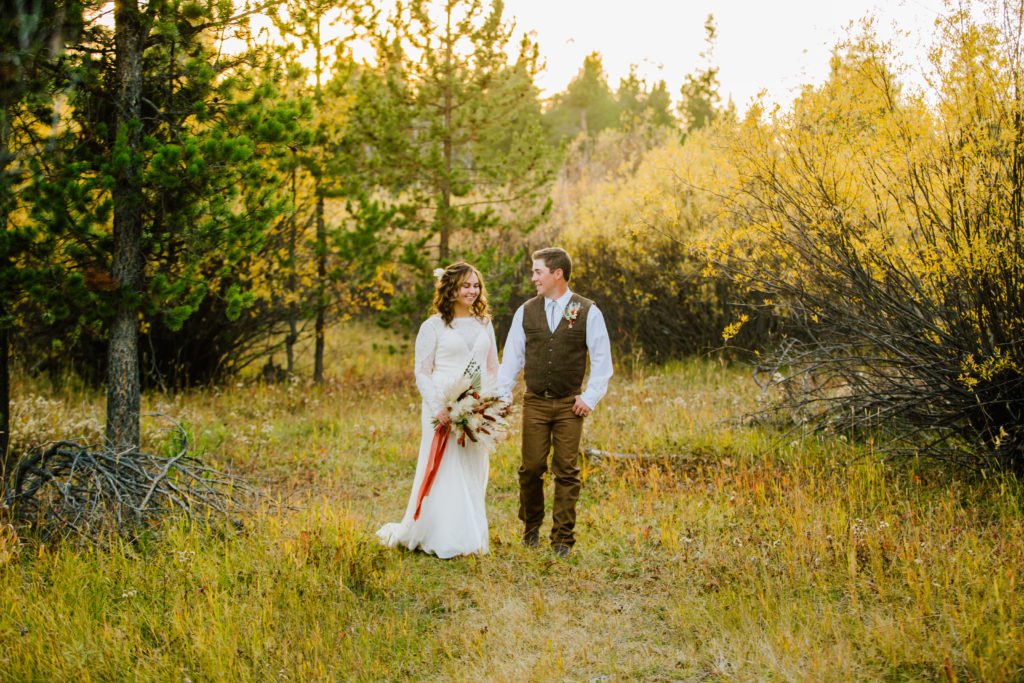 bride and groom walking through forest together 