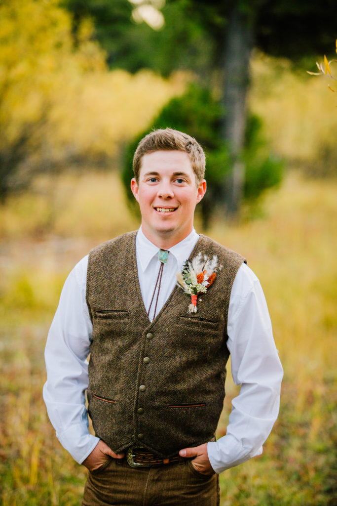 groom smiling wearing brown vest and bolo tie 
