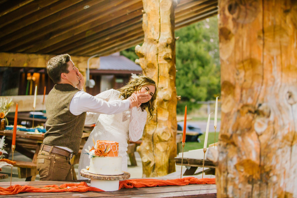 bride and groom smashing cake into one another's faces