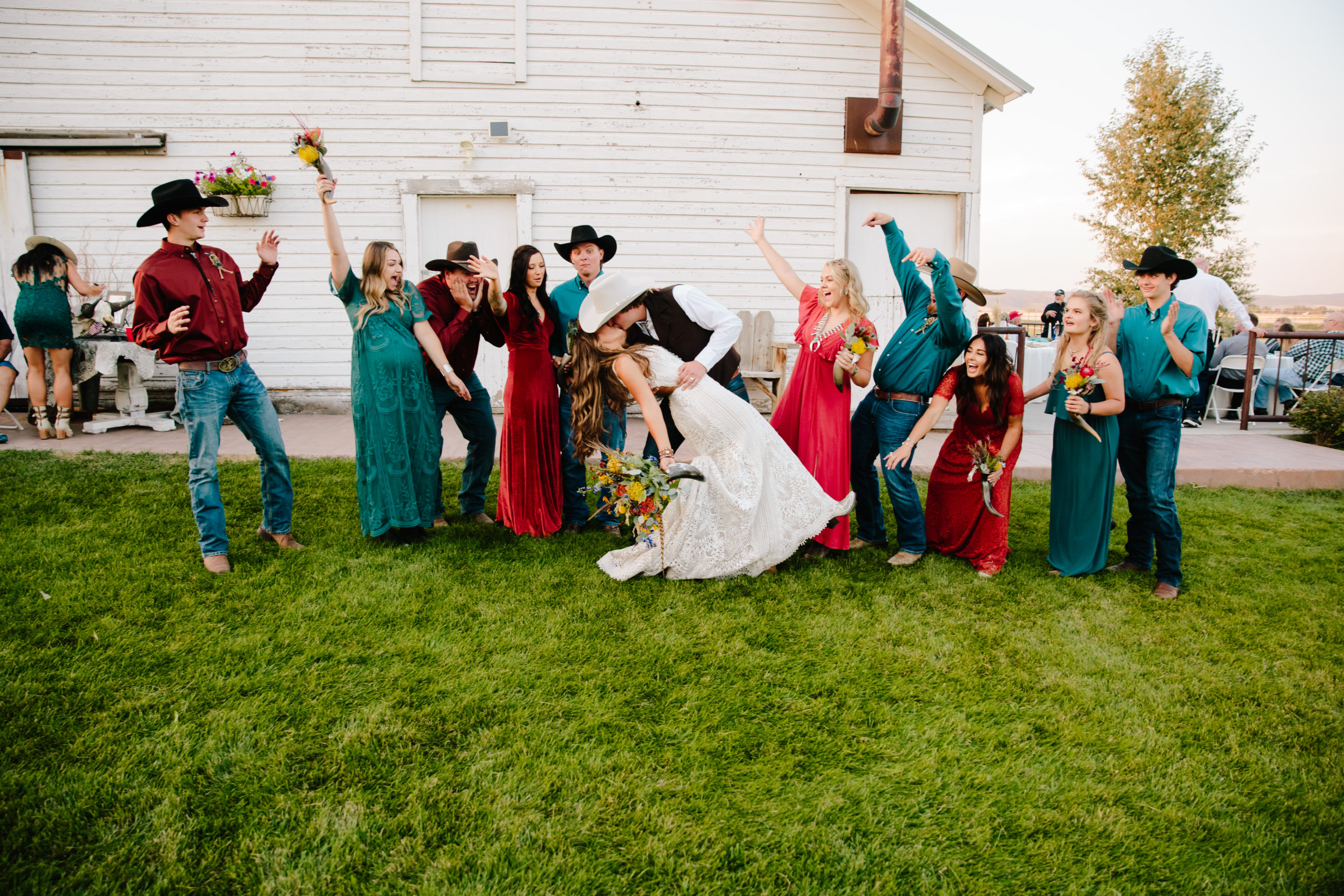 bridal party cheers as bride and groom kiss