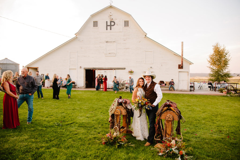 bride and groom posing between saddles during western Island Park wedding day