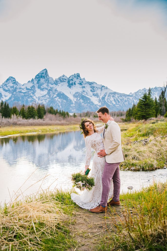 bridal photos with Grand Teton wedding photographers with bride and groom dancing next to a river in front of the mountains