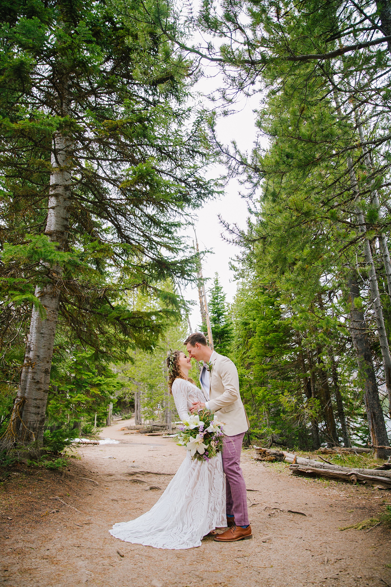 bride and groom kissing on a dirt trail surrounded by the woods 