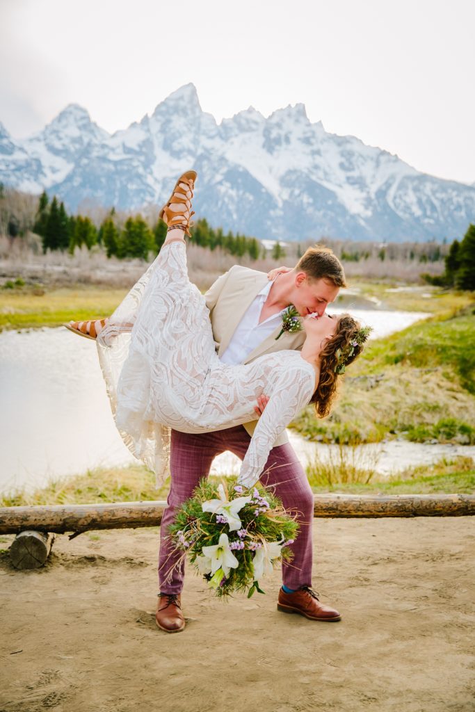 Jackson Hole wedding photographer captures groom lifting bride up and kissing her in grand teton national park