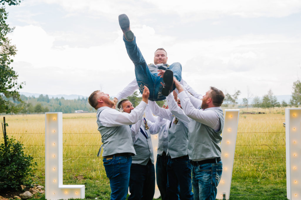 groom being thrown in air by groomsmen