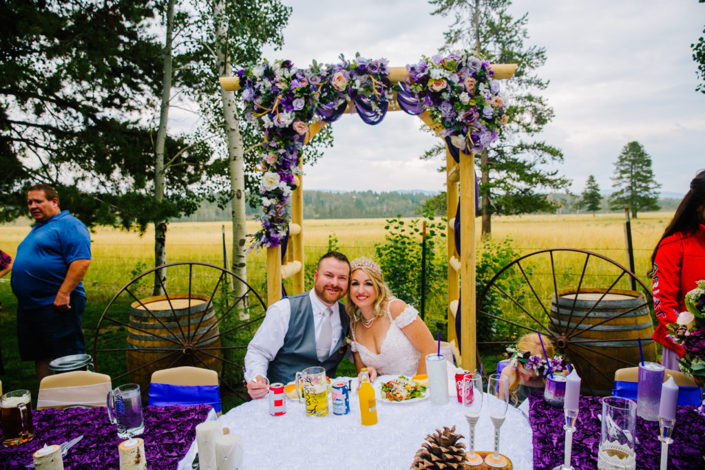 bride and groom sitting at sweetheart's table together during outdoor reception