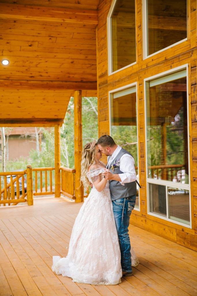 Jackson Hole wedding photographer captures groom dances with his bride on their Pocatello wedding day outside of a cabin