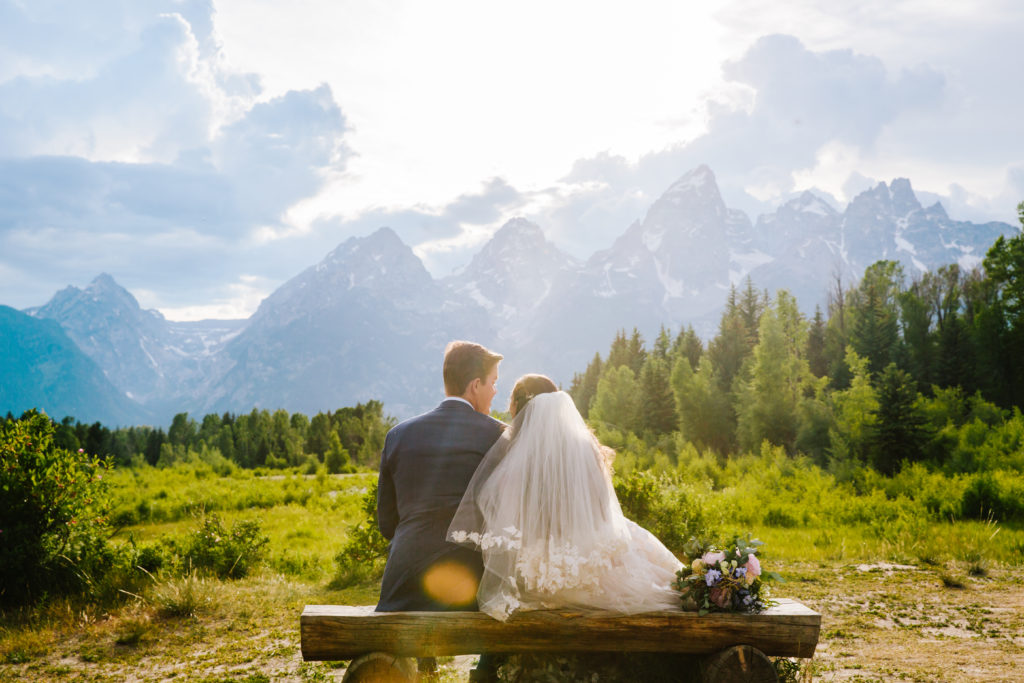 bride and groom sitting on bench in grand teton national park