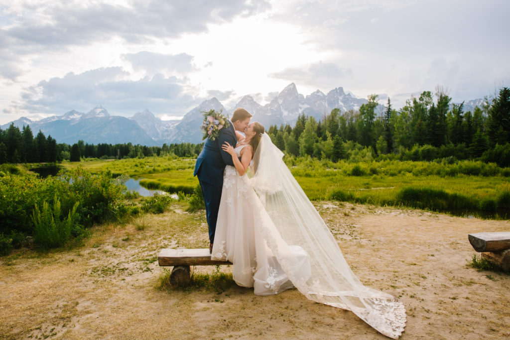 bride and groom kissing on bench 