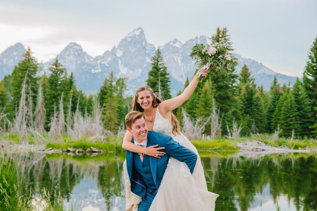 Jackson Hole wedding photographer captures groom lifting bride up on back during outdoor bridals