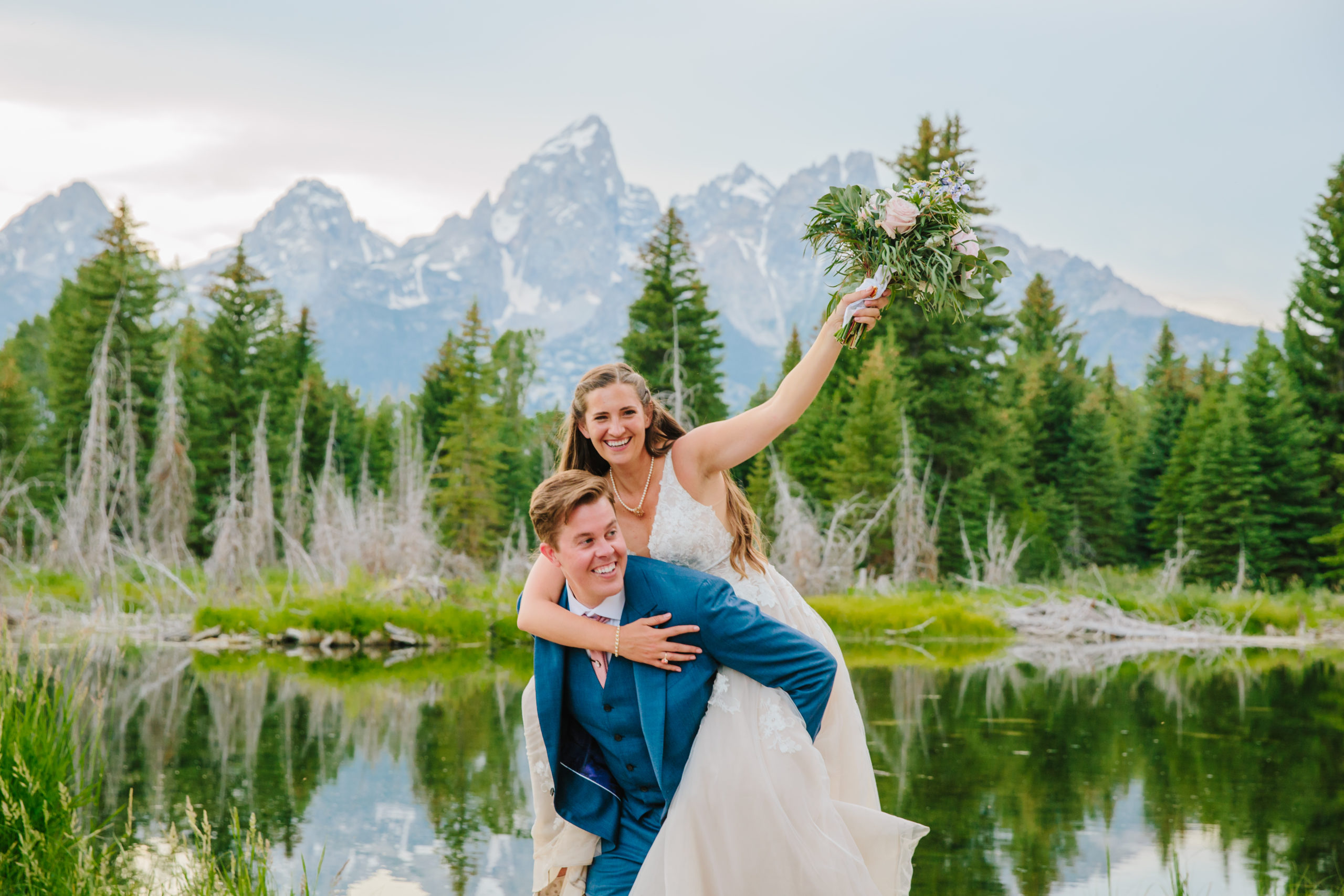 Jackson Hole wedding photographer captures groom lifting bride up on back during outdoor bridals