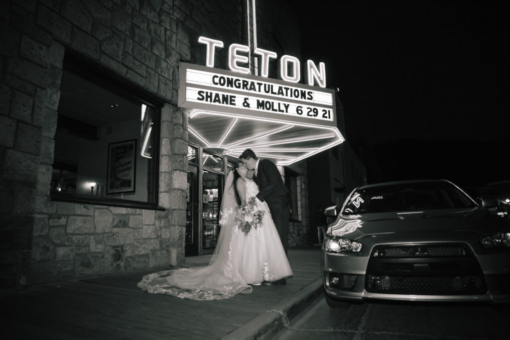 bride and groom kissing under sign at rehearsal dinner in Jackson Hole