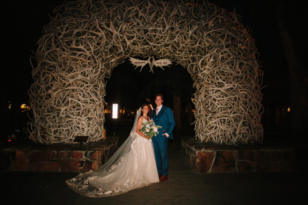 Bride and groom standing in front of Jackson Hole arch after elopement