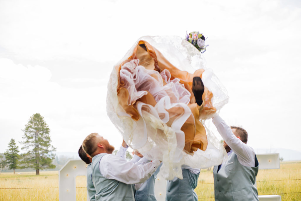 bride being thrown in air by groomsmen