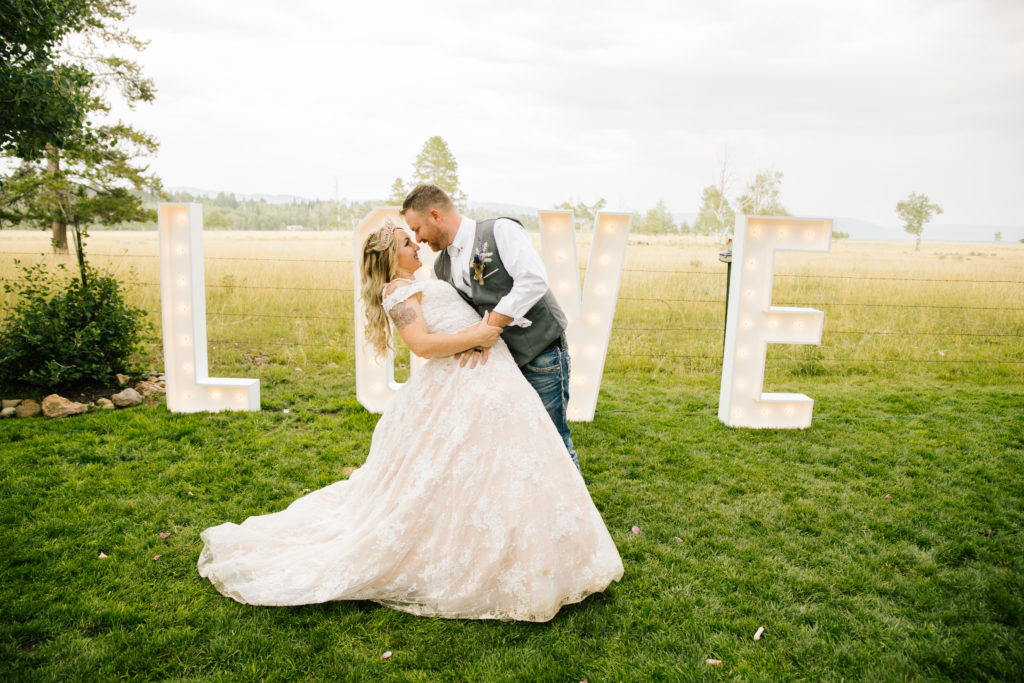 bride and groom kissing in front of 'love' sign on island park cabin wedding day