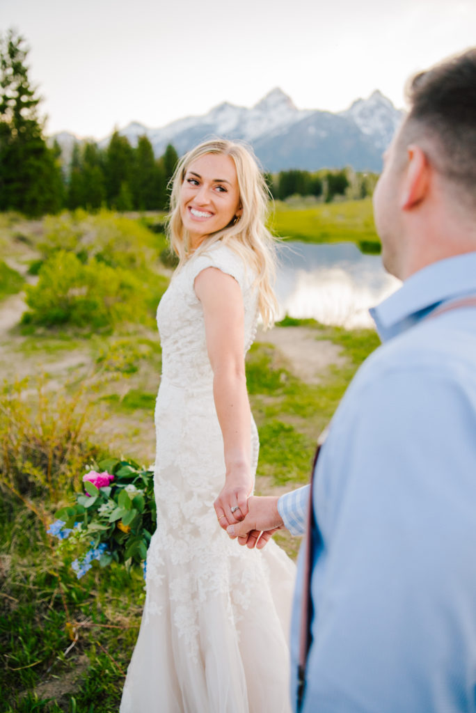 Jackson Hole wedding photographer captures bride leading groom off into grand teton national park