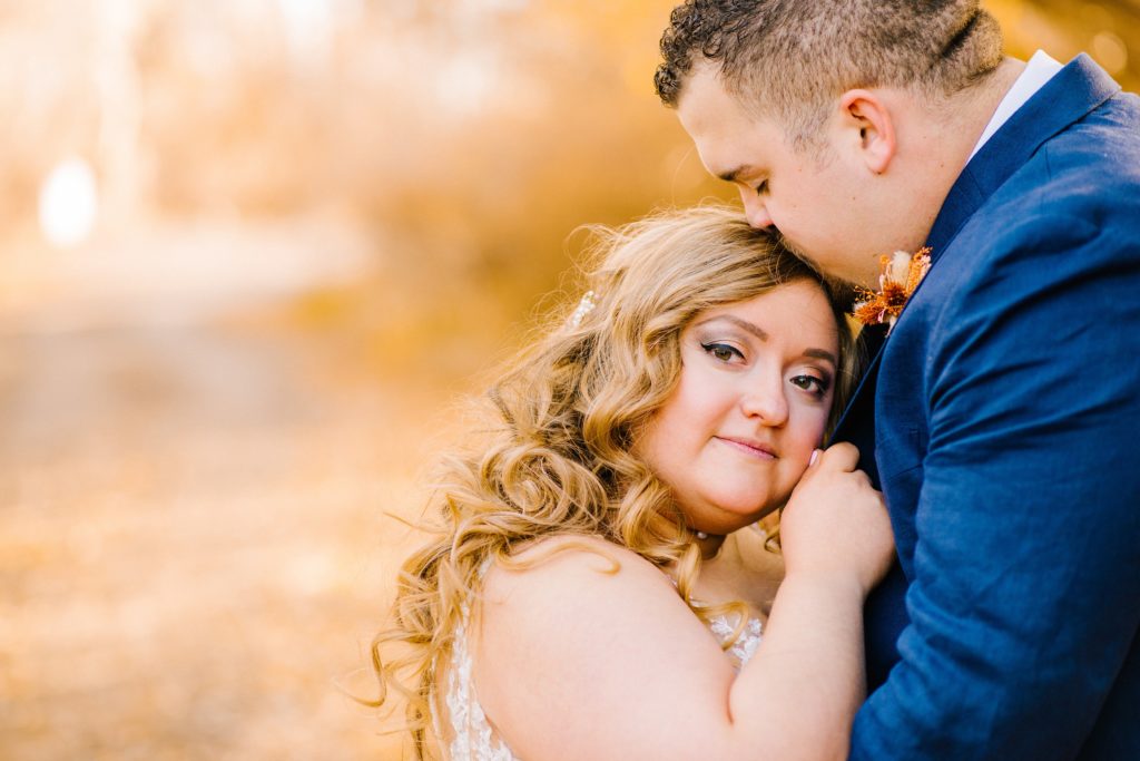 Jackson Hole wedding photographer captures bride looking at camera holding onto groom's jacket