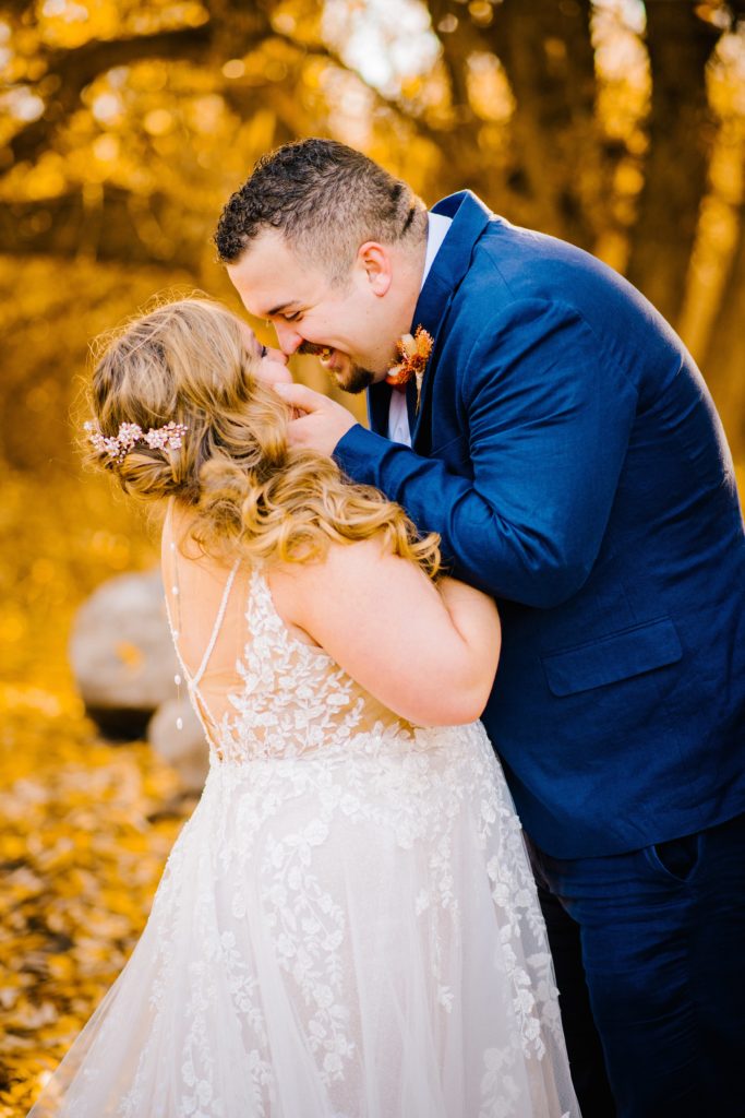 Jackson Hole wedding photographer captures bride and groom hugging and kissing during portraits