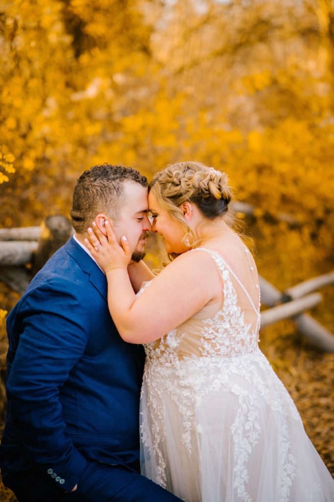 Jackson Hole wedding photographer captures bride holding grooms cheeks and resting her forehead against her grooms during their fall wedding in the woods