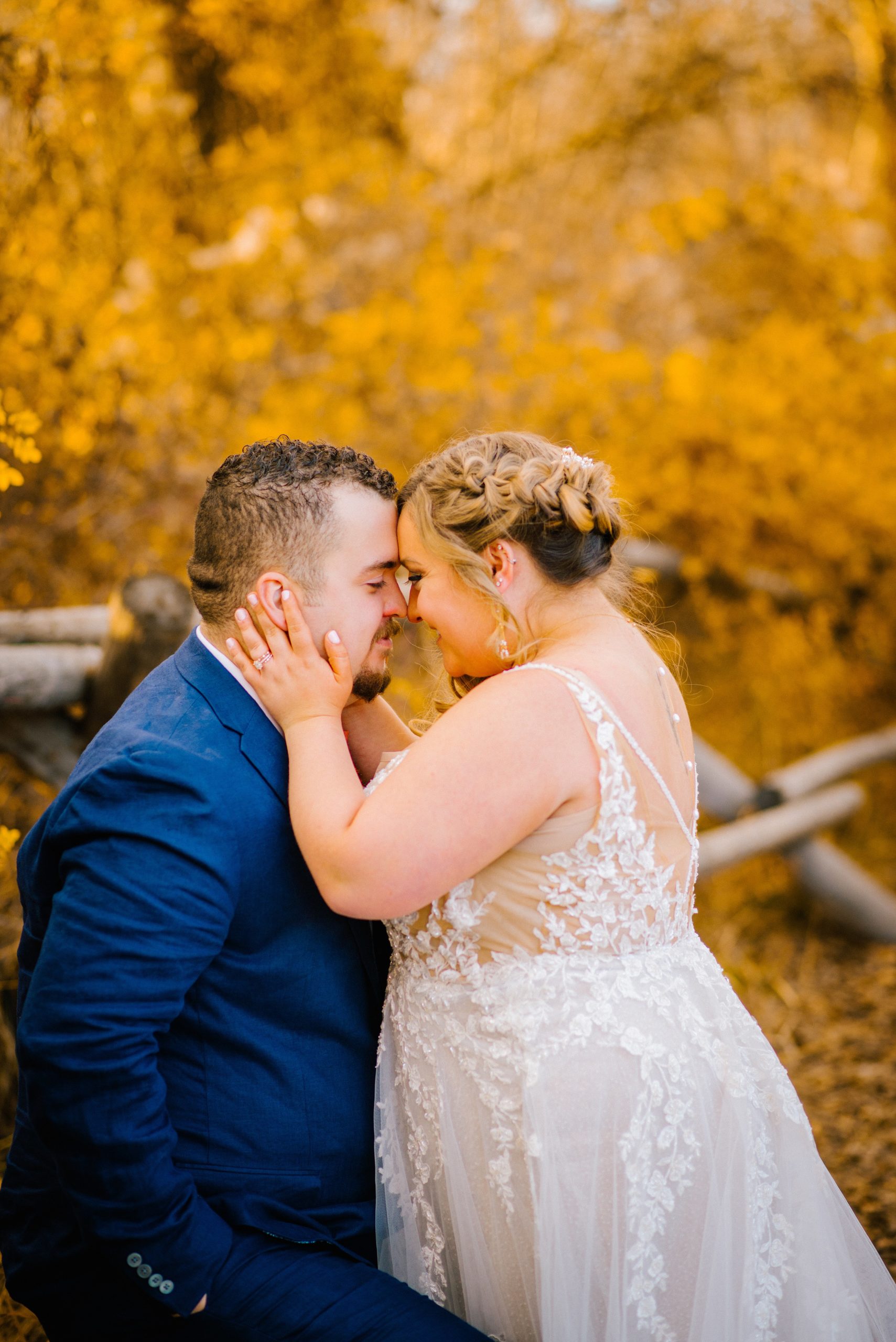 bride holding grooms cheeks and resting her forehead against her grooms during their fall wedding in the woods