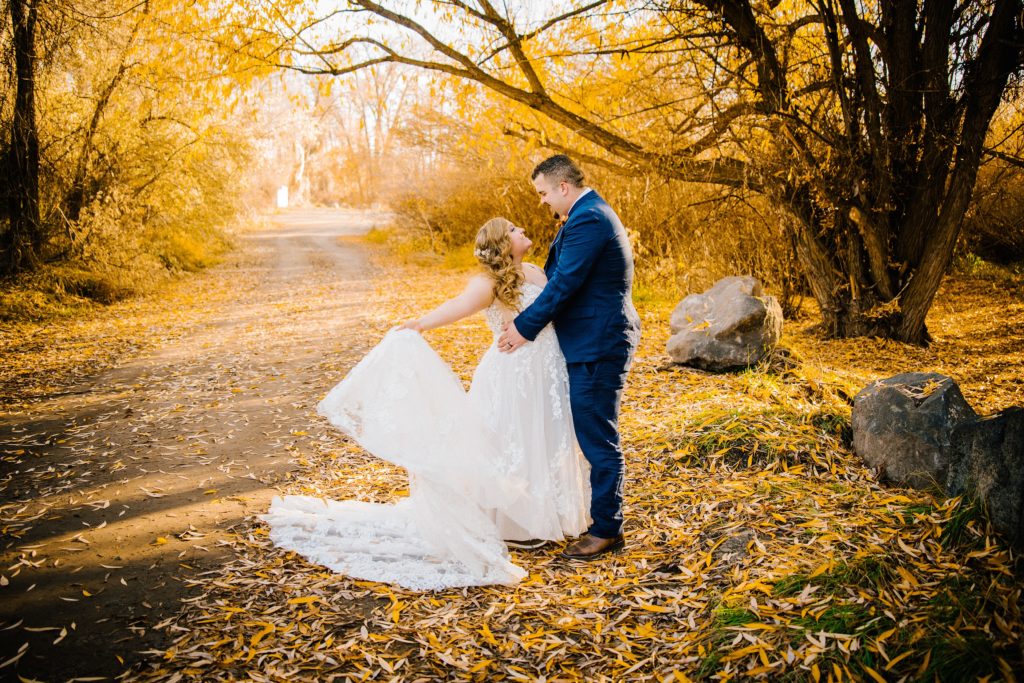fall elopement in the woods during the fall with bride adn groom hugginand bride dress flowing 