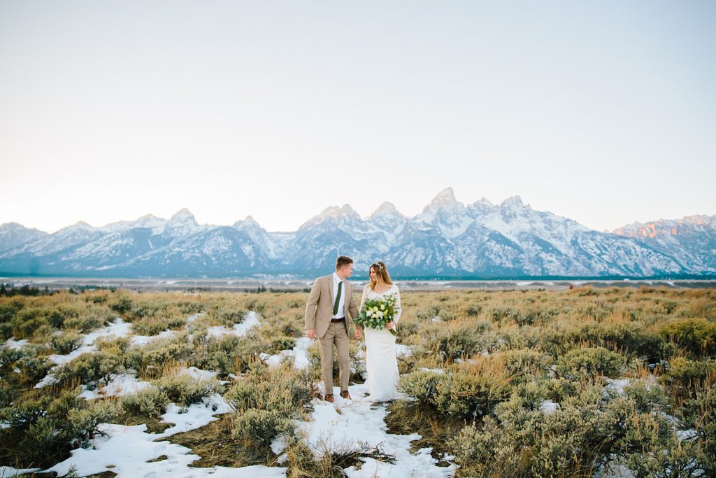 Jackson Hole wedding photographer captures bride and groom walking through grand teton national park