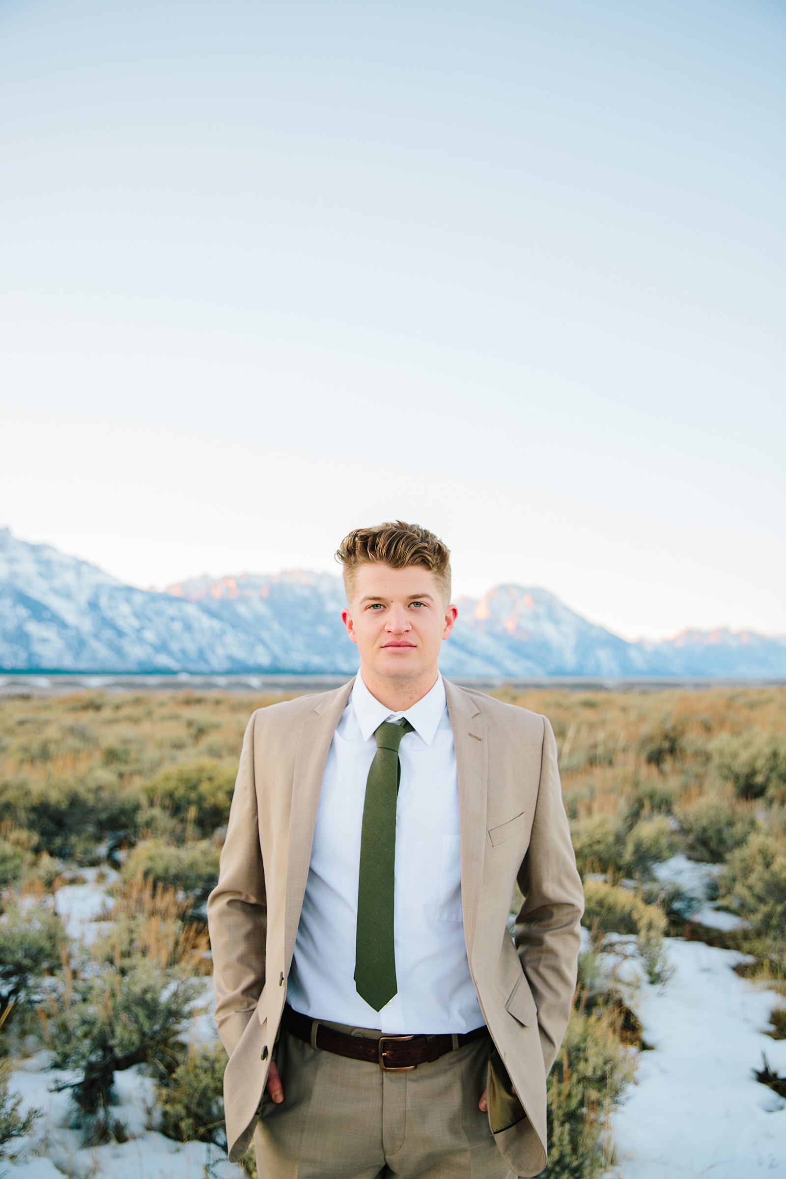 groom in a tan suit standing with his hands in his pockets for his Pocatello Idaho wedding